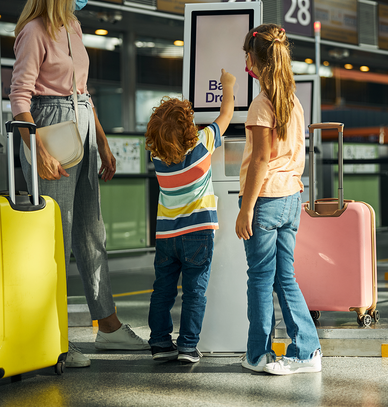 curious-boy-touching-screen-bag-drop-kiosk.png 